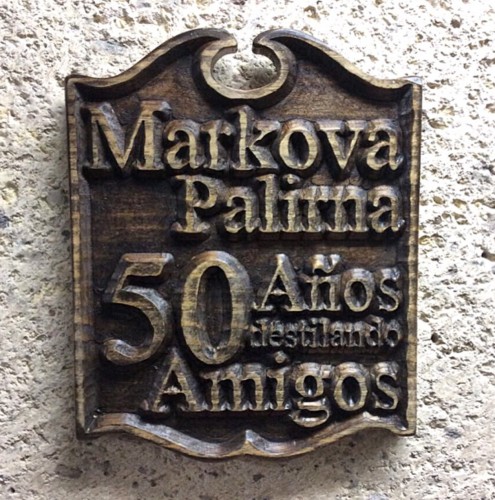 Cartel de madera labrado con el nombre 'Markova Palima' y el lema '50 Años destilando Amigos'.