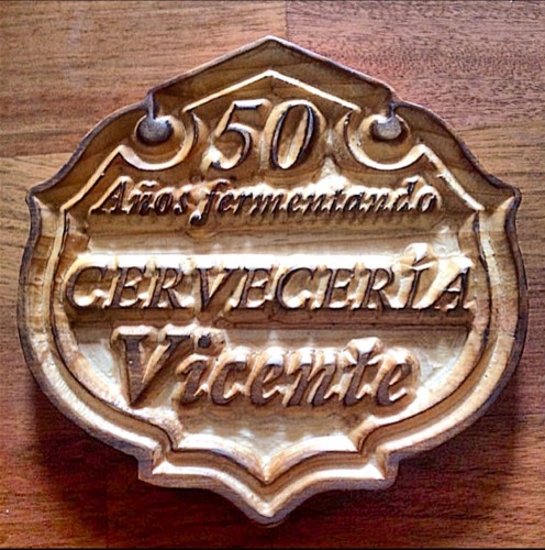 Rótulo de madera grabado con el texto '50 Años fermentando Cervecería Vicente'.