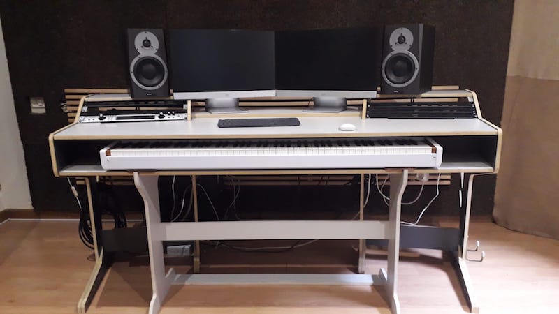 Estación de trabajo de grabación musical con un teclado electrónico y monitores de audio.