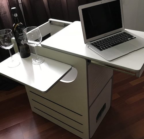 Mueble camper blanco multifuncional con una laptop y dos copas de vino sobre él.
