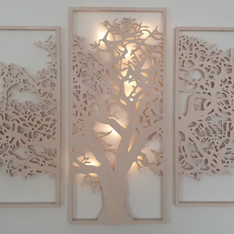 Tres paneles decorativos montados en la pared, con el central iluminado desde atrás, mostrando un diseño de árbol de la vida.