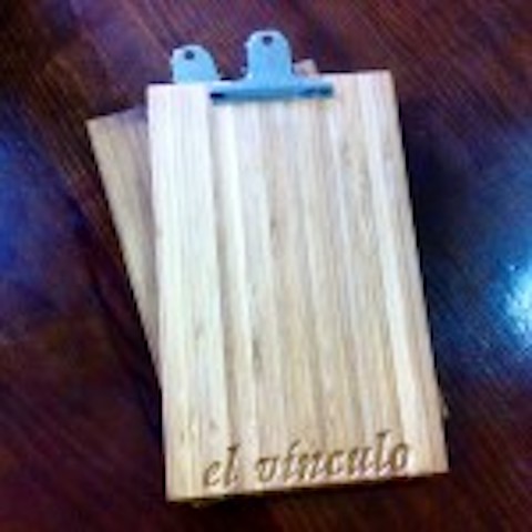 Portacomandas de madera con clip metálico para sujetar papeles en un restaurante.