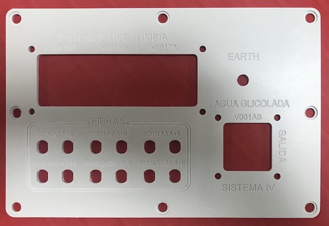 Panel frontal de equipo con ventanas de acrílico rojo y etiquetas para conexiones.