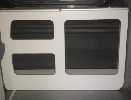 Panelado interior de una furgoneta con secciones de tapicería negra y marco blanco.