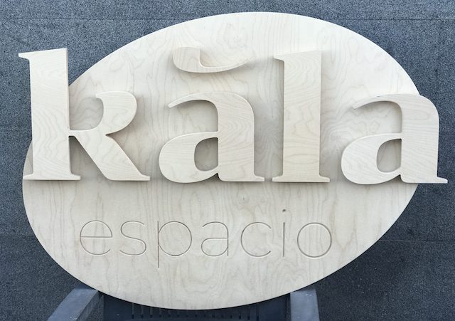 Rótulo de madera con el nombre 'Kala espacio' en relieve sobre un fondo claro.